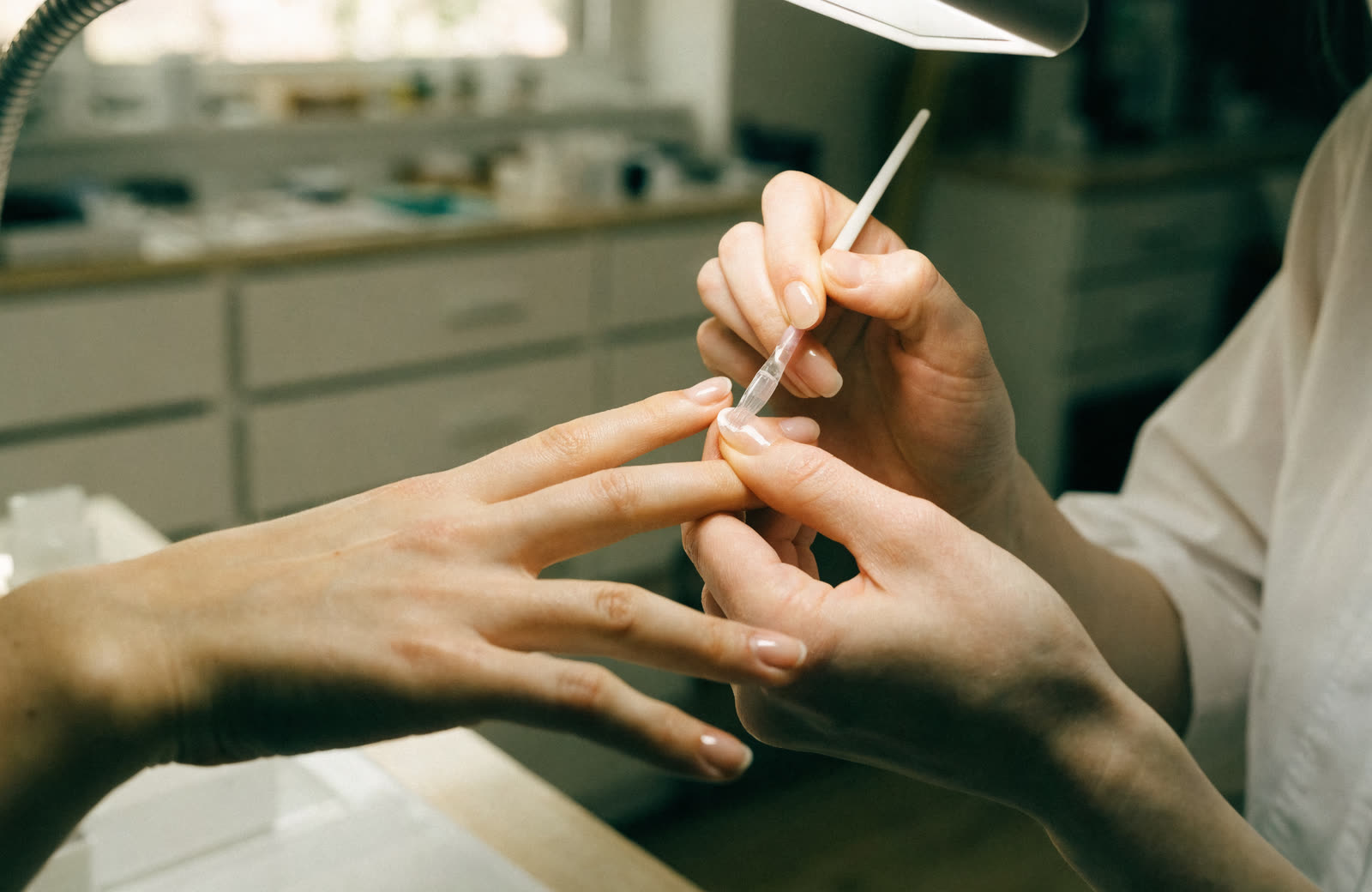 A nail technician shaping a client’s nails at the table.